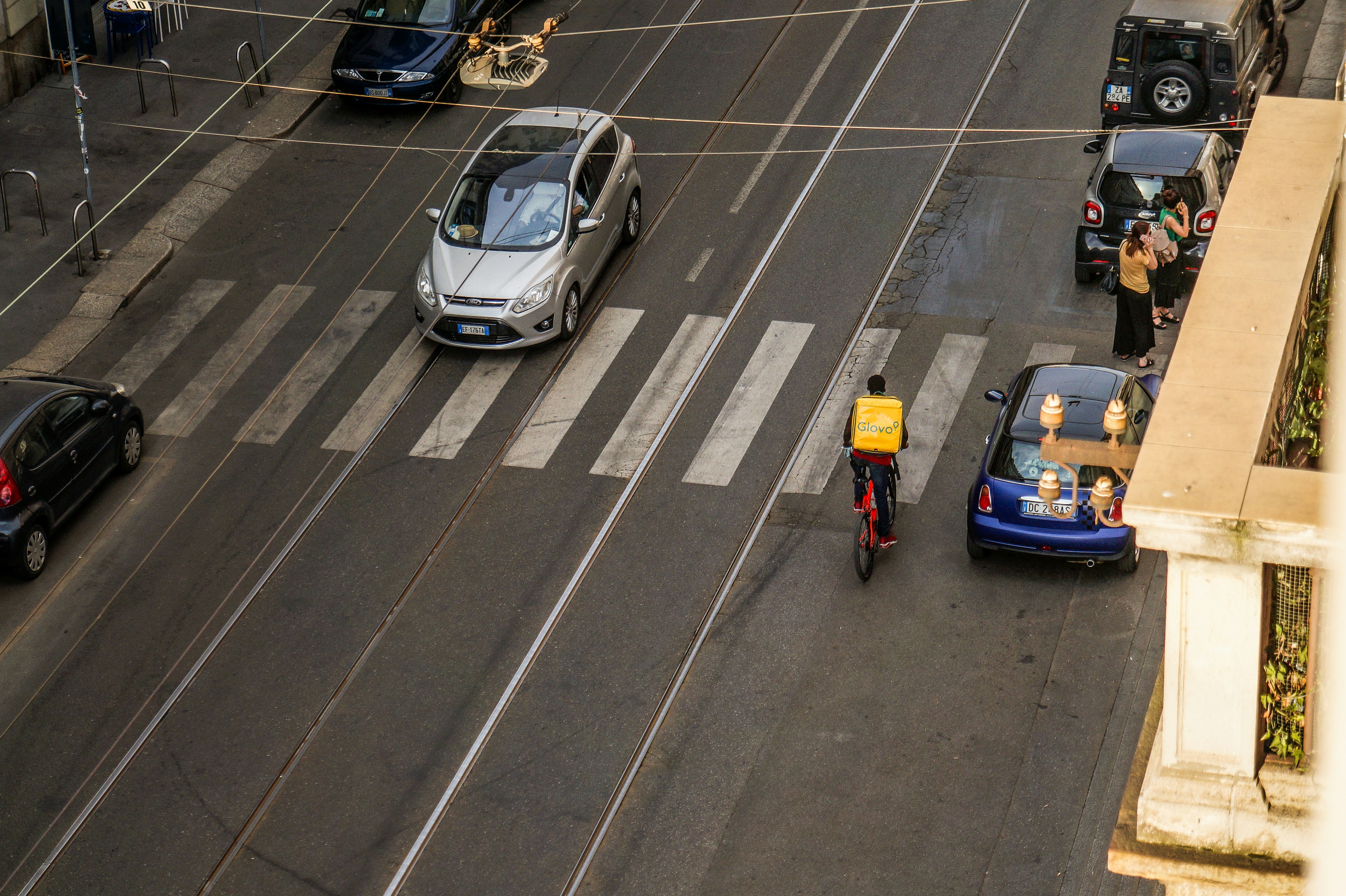 Delivery person on scooter crosses street near cars